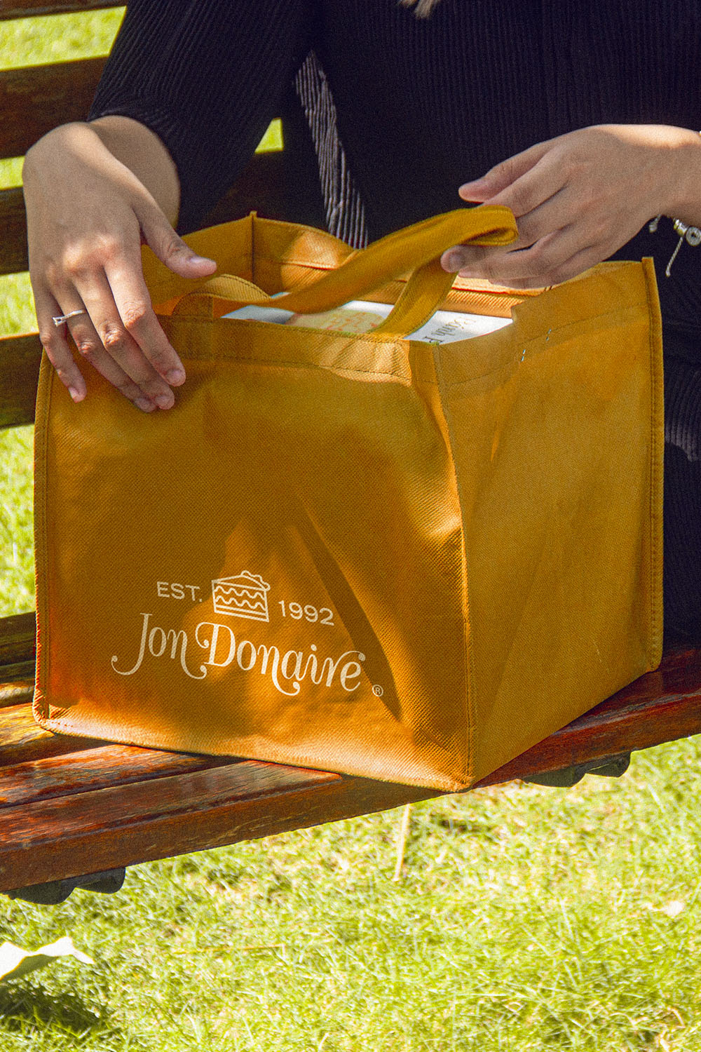 Women open a tote bag full of Jon Donaire frozen cakes by Rich Products outdoor